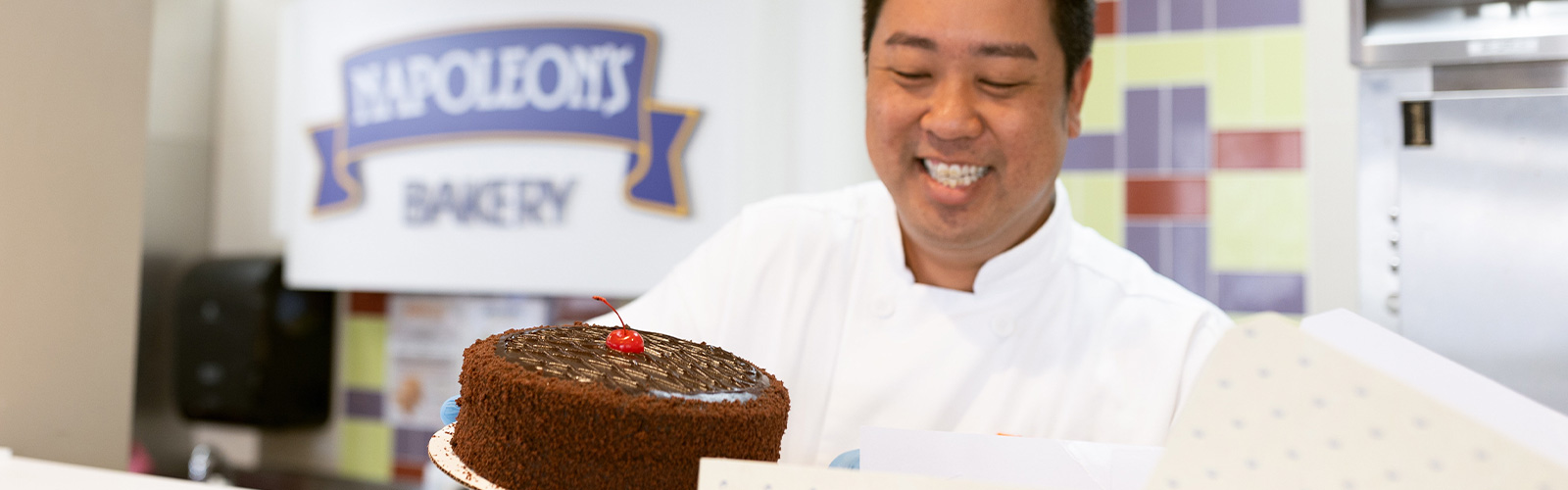 pastry chef from Napoleon's Bakery boxing a cake